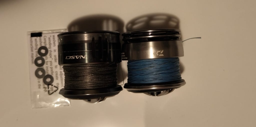Vergleich der Schnurverlegung von Shimano Nasci und Daiwa Exceler mit sichtbaren Unterlegscheiben zur Justierung der Nasci-Spule.